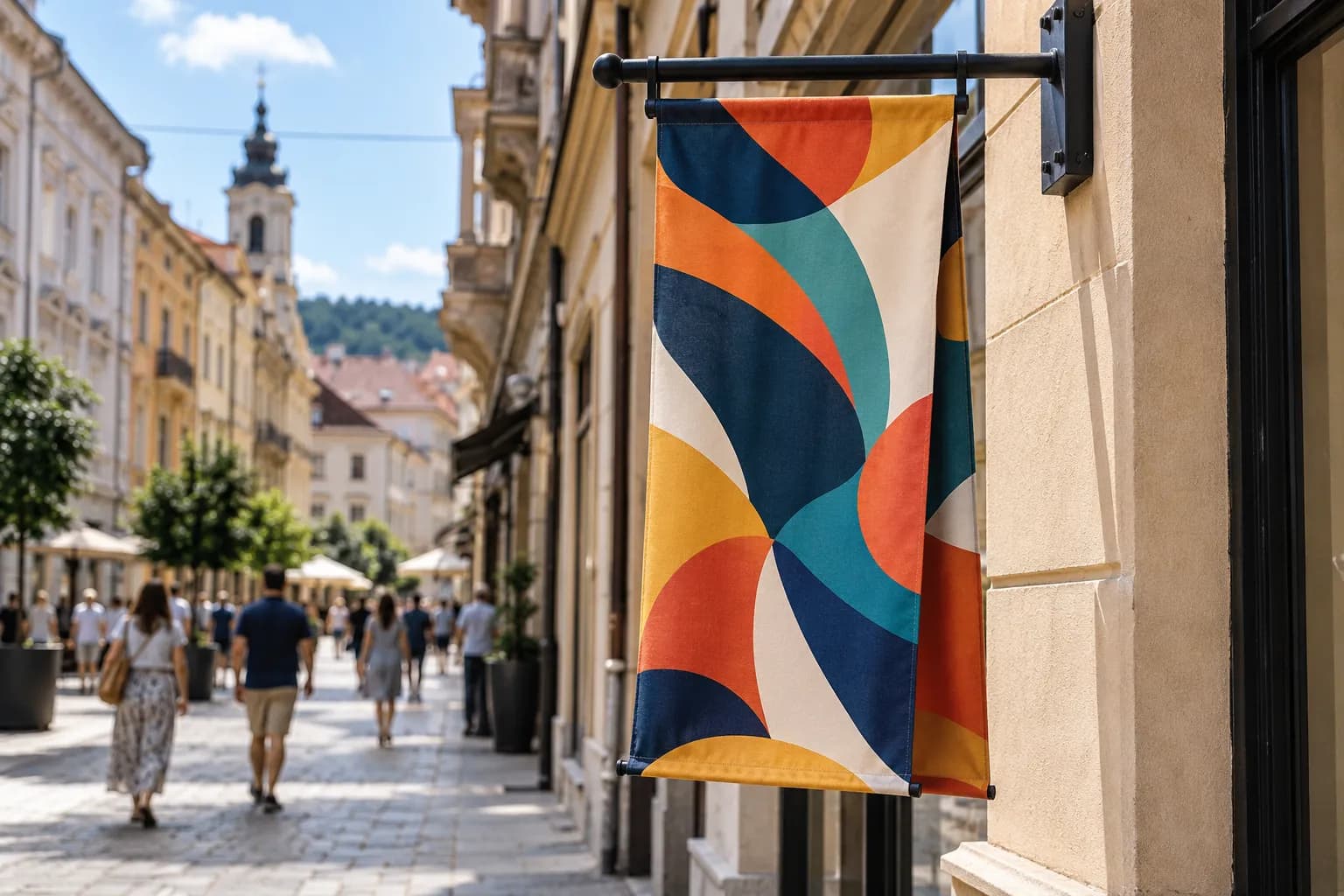 Banner față-verso cu grafică abstractă, prins pe un braț metalic perpendicular pe fațada unui magazin, pe o stradă pietonală